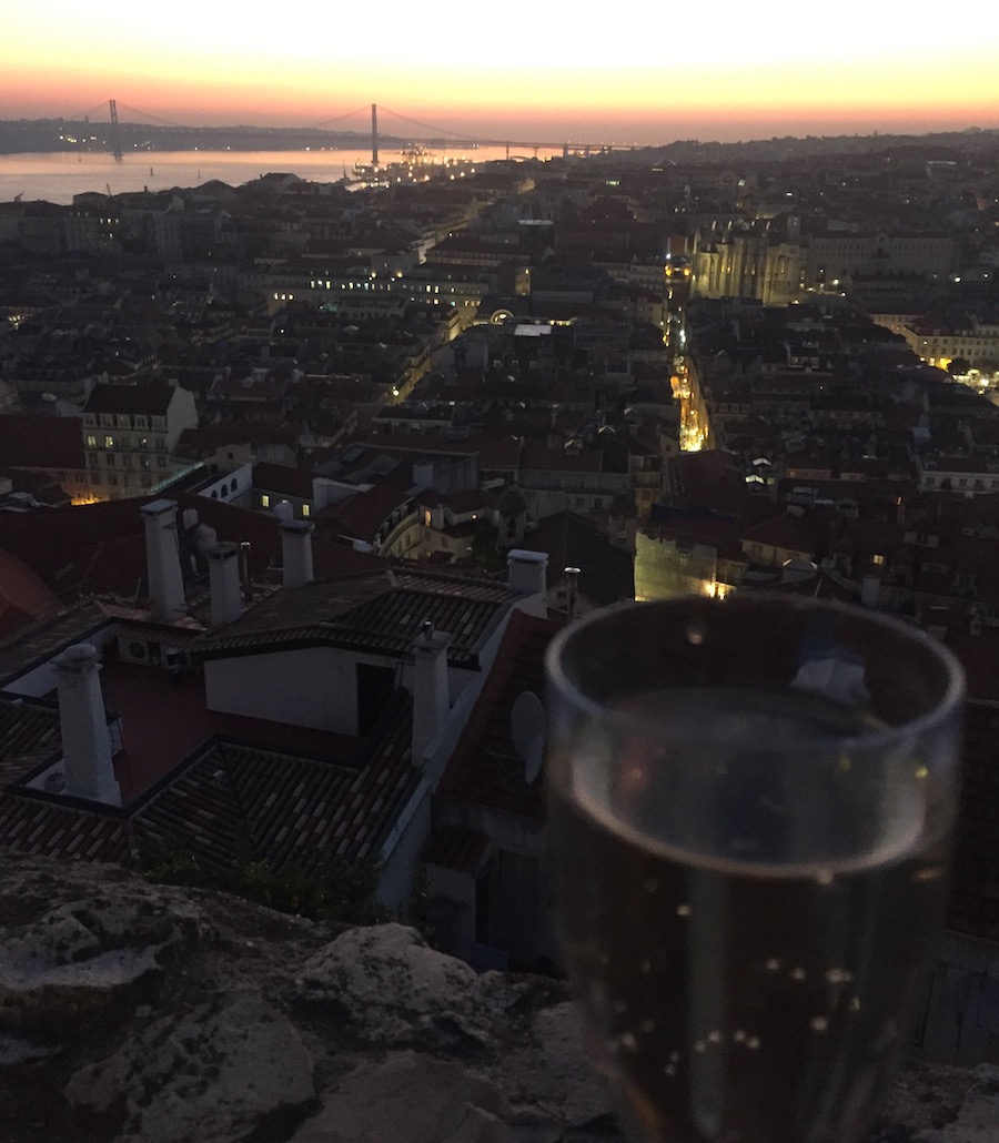 With a glass of wine overlooking St. Jorge's Castle in Lisbon at night